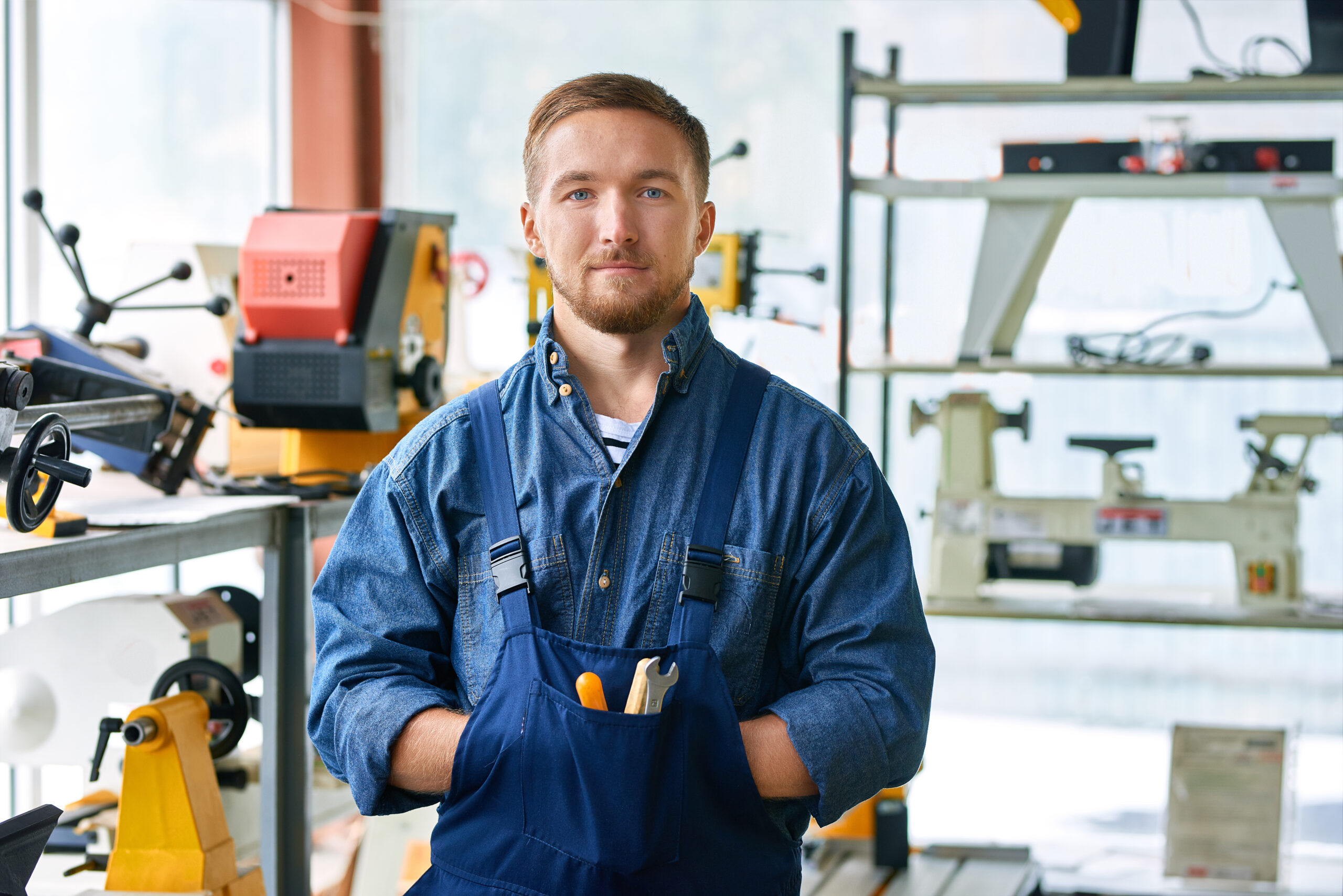 Mechanic Posing at Modern Factory Waist up portrait of young mechanic posing looking at camera standing in industrial workshop, copy space